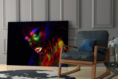 Vibrant neon-colored glass wall art depicting an abstract female face with blue, red, green, and yellow hues displayed in a modern living room setting.