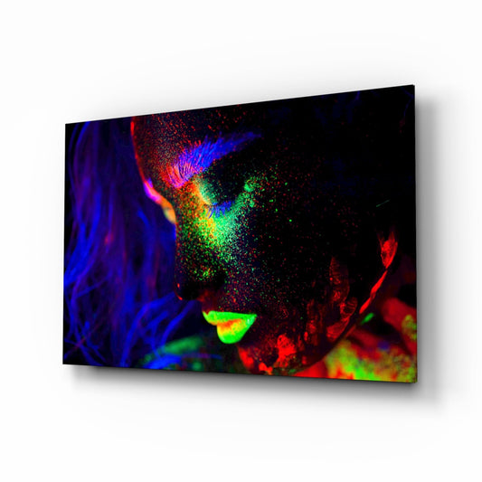 Colorful neon portrait on glass wall art displaying vibrant blue, red, green, and yellow fluorescent paint effects against black background.