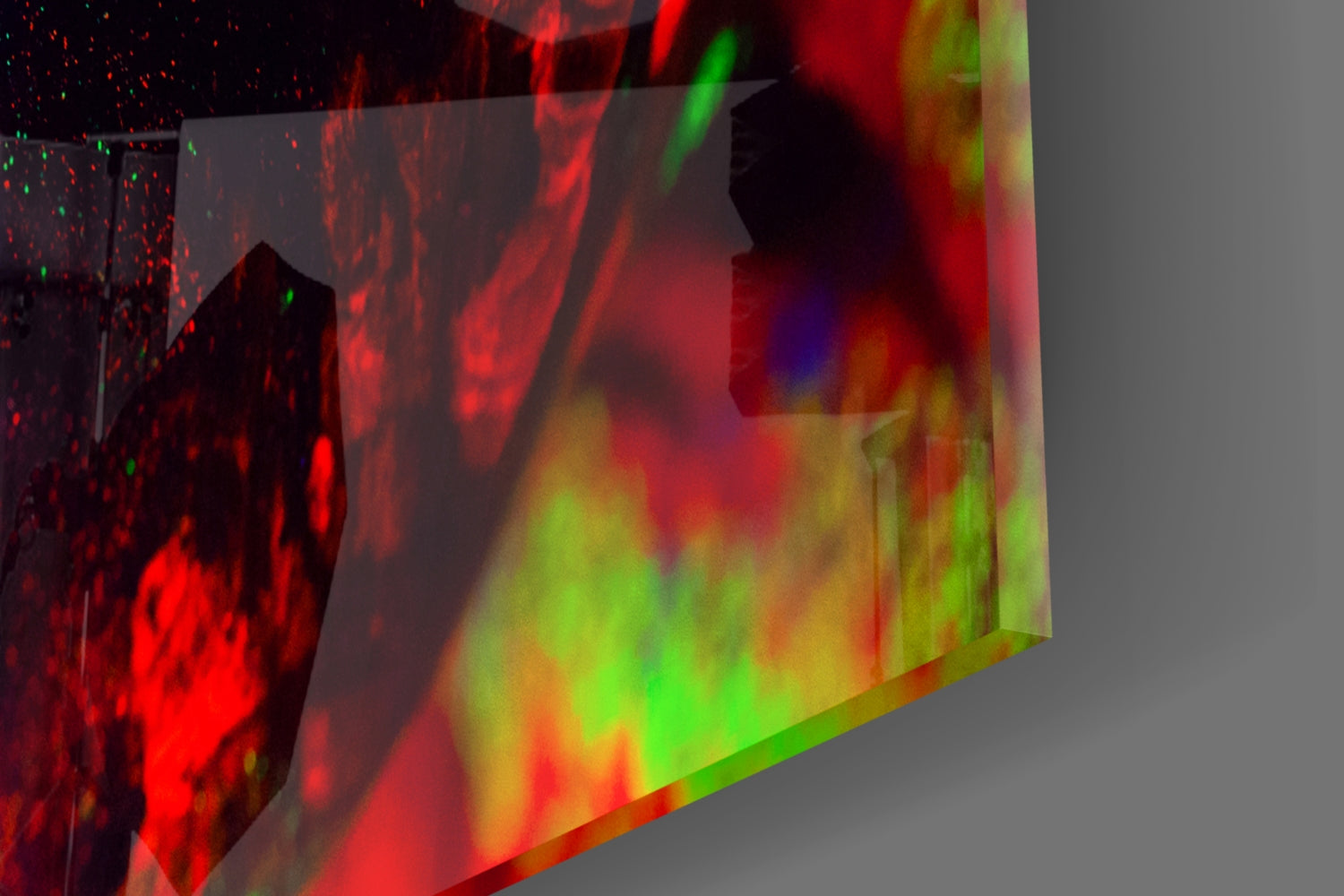 Angled view of glass wall art displaying vibrant red, green, and yellow layered colors with particle effects and silhouetted profile.