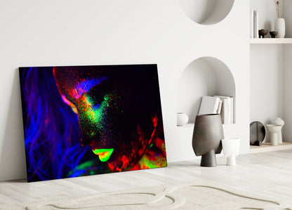 Colorful abstract glass art leaning against white wall in minimalist interior setting with decorative objects.