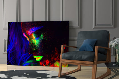 Colorful abstract portrait glass art displayed on wall in modern living room with wooden chair and geometric patterned rug.