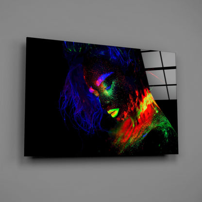 Angled 3/4 view of glass wall art displaying neon-colored female portrait with vibrant blue, red, green, and yellow fluorescent paint effects on black background.
