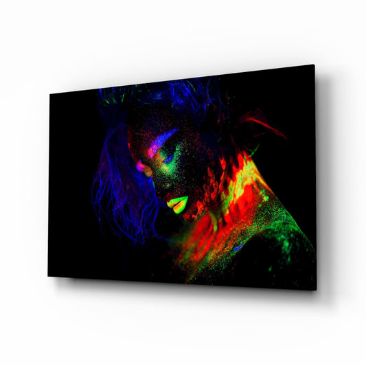 Angled view of glass wall art depicting a colorful female portrait with vibrant blue, red, green, and yellow neon-style lighting against black background.