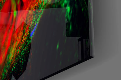Close-up angled view of colorful glass wall art with red, green, and blue light projections on textured surface.
