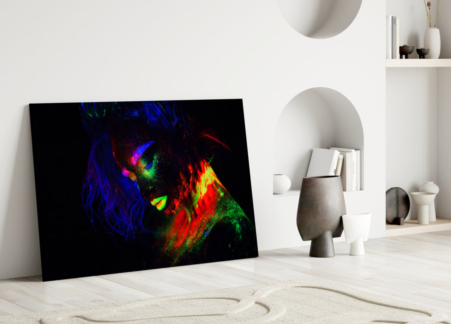 Colorful neon portrait of a woman's face displayed on black glass leaning against white interior wall.