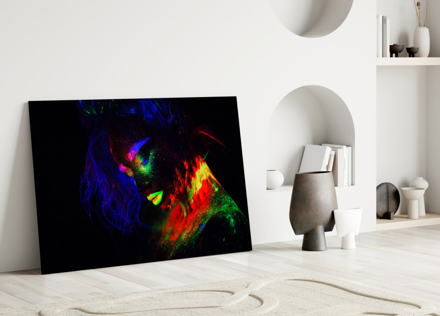 Colorful neon portrait of a woman's face displayed on black glass leaning against white interior wall.