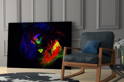 Neon-colored glass wall art depicting an abstract female portrait in vibrant blues, reds, greens, and yellows displayed in a modern living room setting.