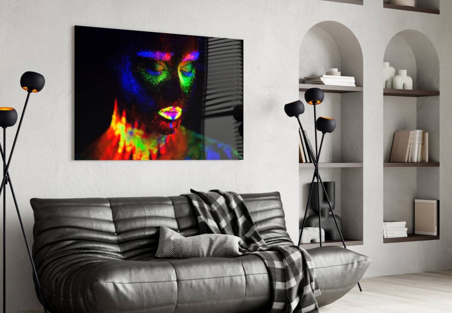 Colorful neon portrait of a woman's face displayed as glass wall art above a gray leather sofa in a modern living room.