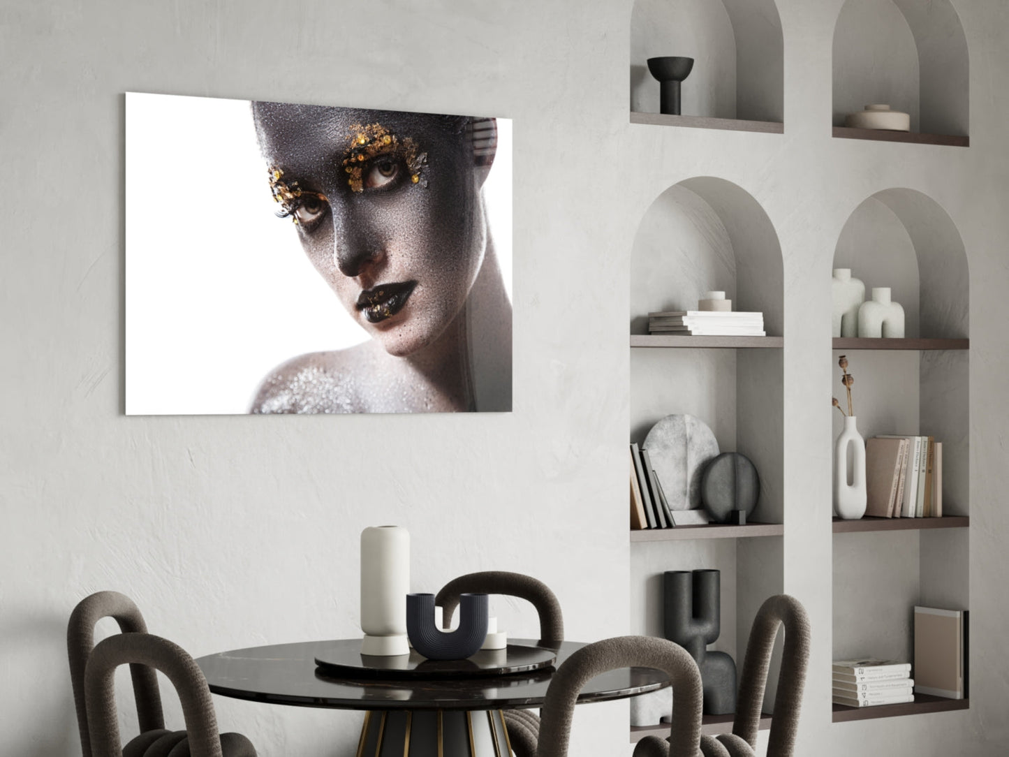 Glass wall art featuring portrait of woman with gold leaf eye makeup and silver glitter against white background, displayed above dining table.