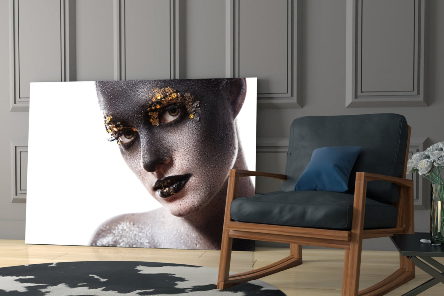 Glass wall art featuring a woman's face with black and gold glitter makeup displayed in a modern interior setting.