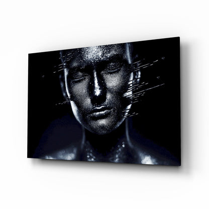 Glass wall art displaying a monochromatic portrait of a woman's face with silver sparkle effects and dark background, mounted at an angle.