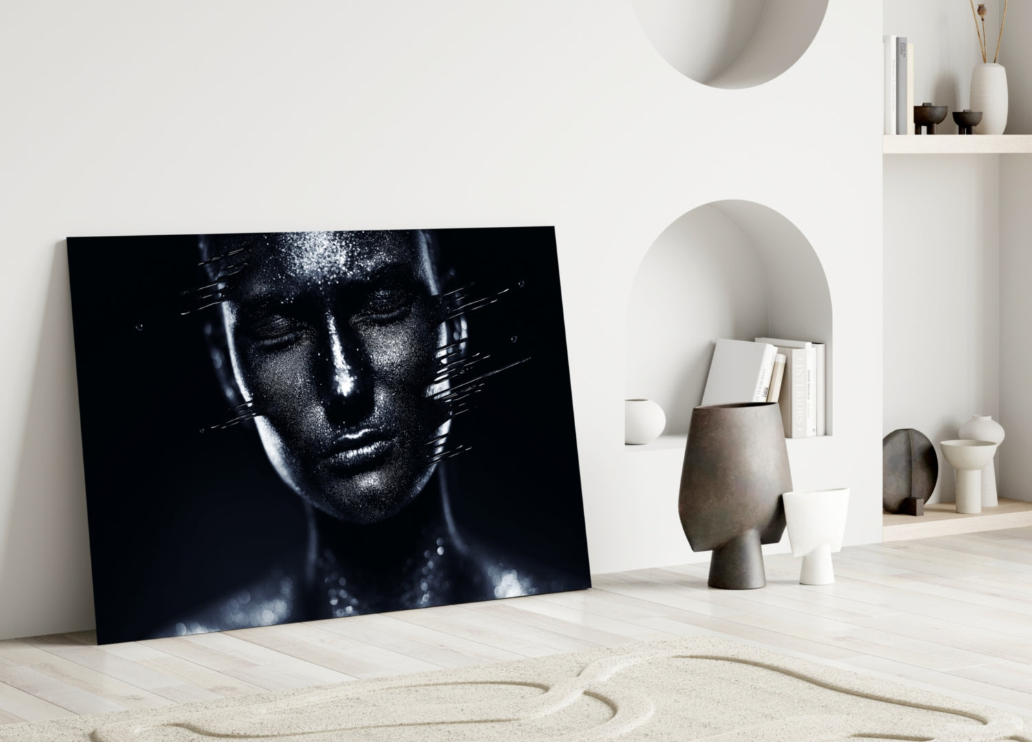 Black and white glass portrait of a woman's face leaning against a white wall in a minimalist interior setting.