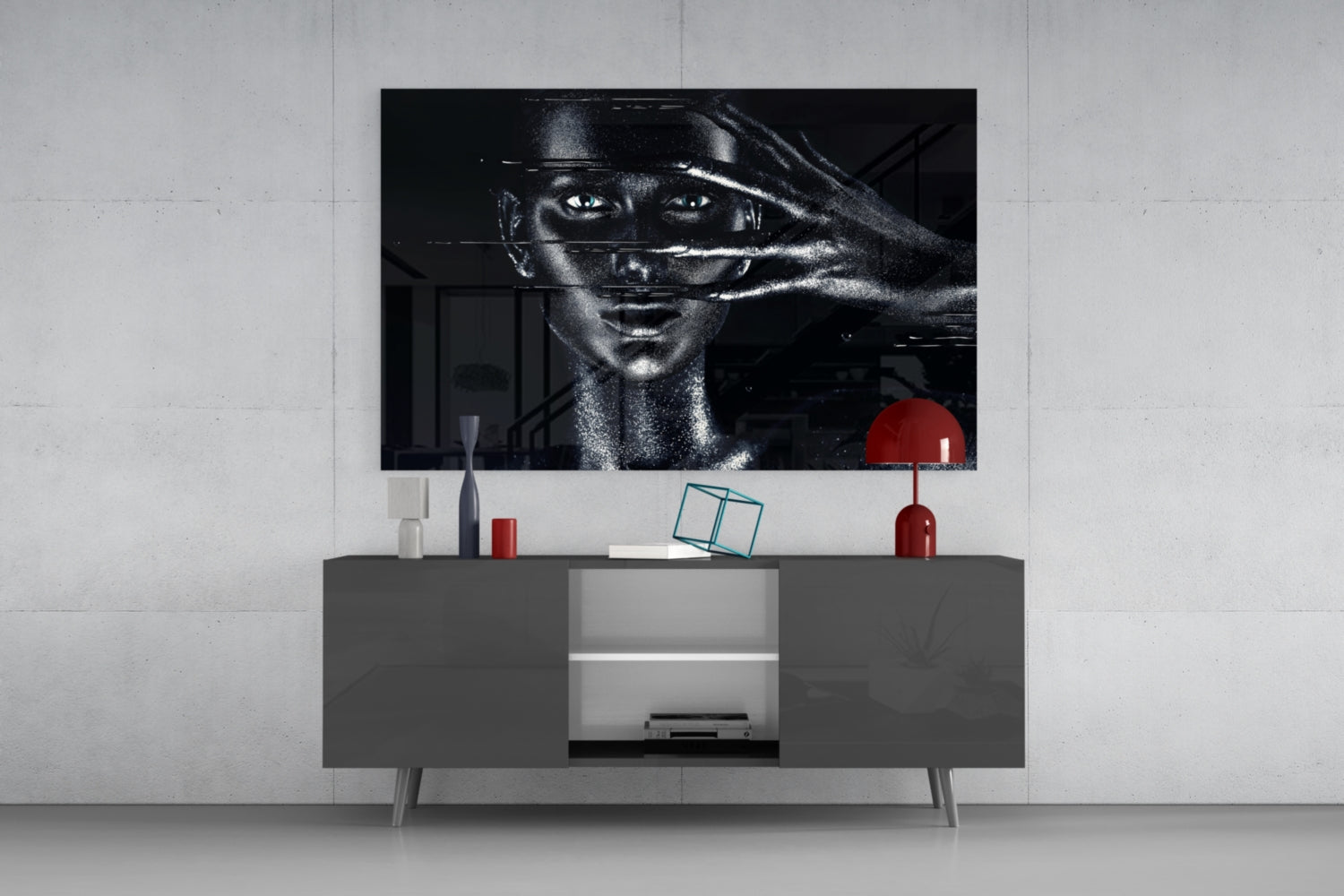 Black and white female portrait glass wall art displayed above gray media console with red decorative accessories.