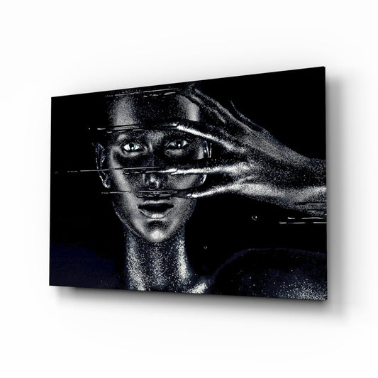Black and white glass wall art featuring a woman's face with geometric lines crossing her eyes and face, displayed at an angle against a white background.