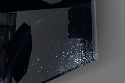 Close-up angle of textured glass wall art showing speckled white particles embedded in dark surface with light gray background.