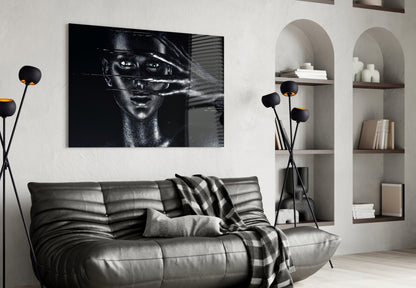 Black and white glass portrait artwork hung above a gray leather sofa in a modern living room with built-in shelving.