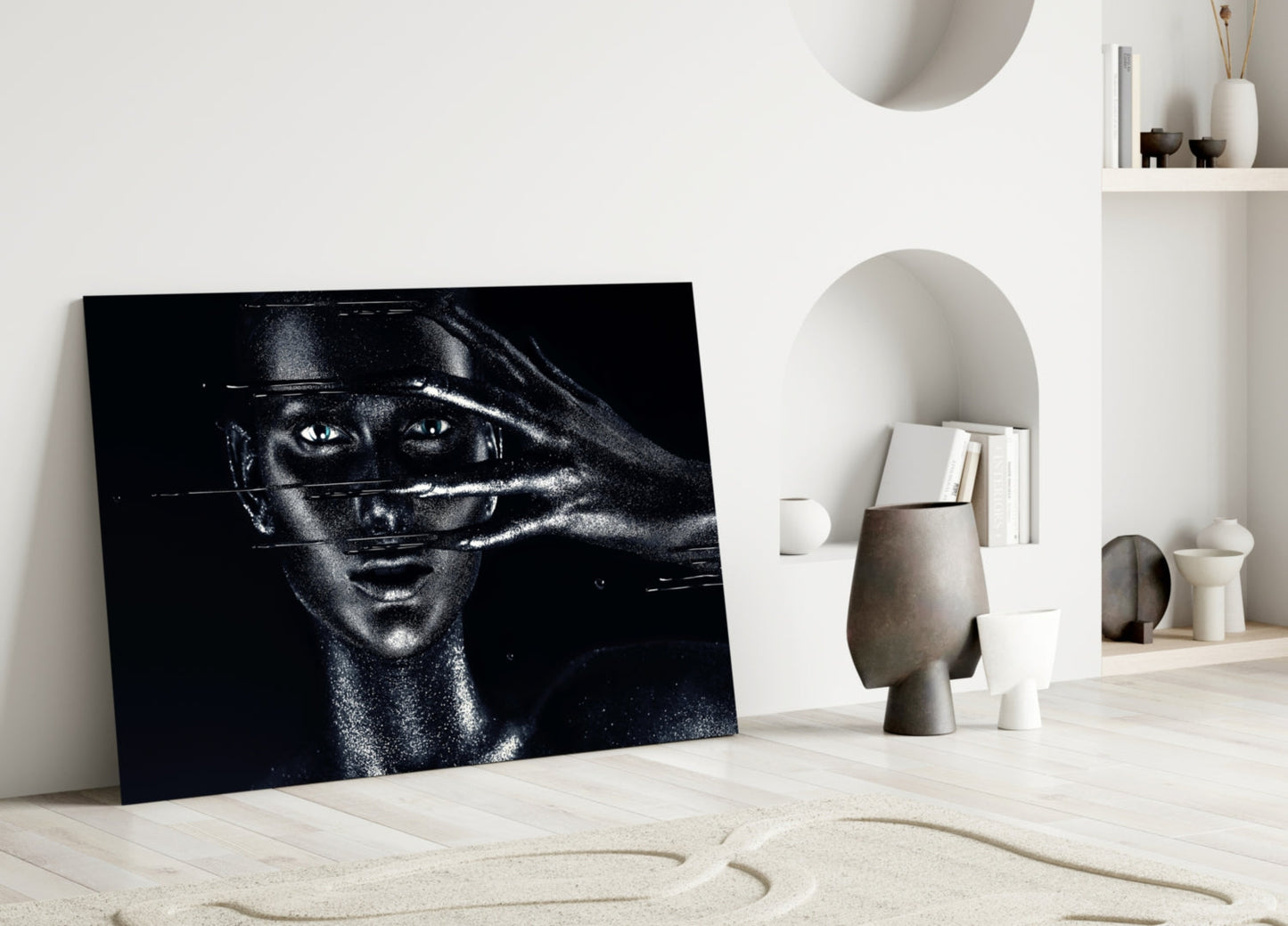 Black and white glass portrait leaning against white wall in minimalist room setting with sculptural décor.