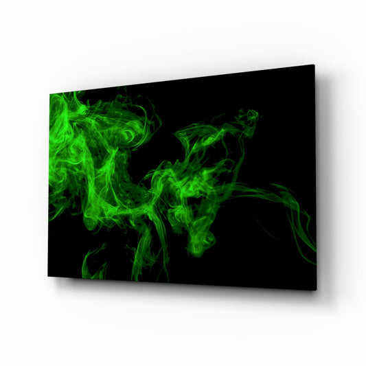 Angled perspective view of black glass wall art panel with vibrant green ethereal smoke swirls against dark background, mounted on white wall.