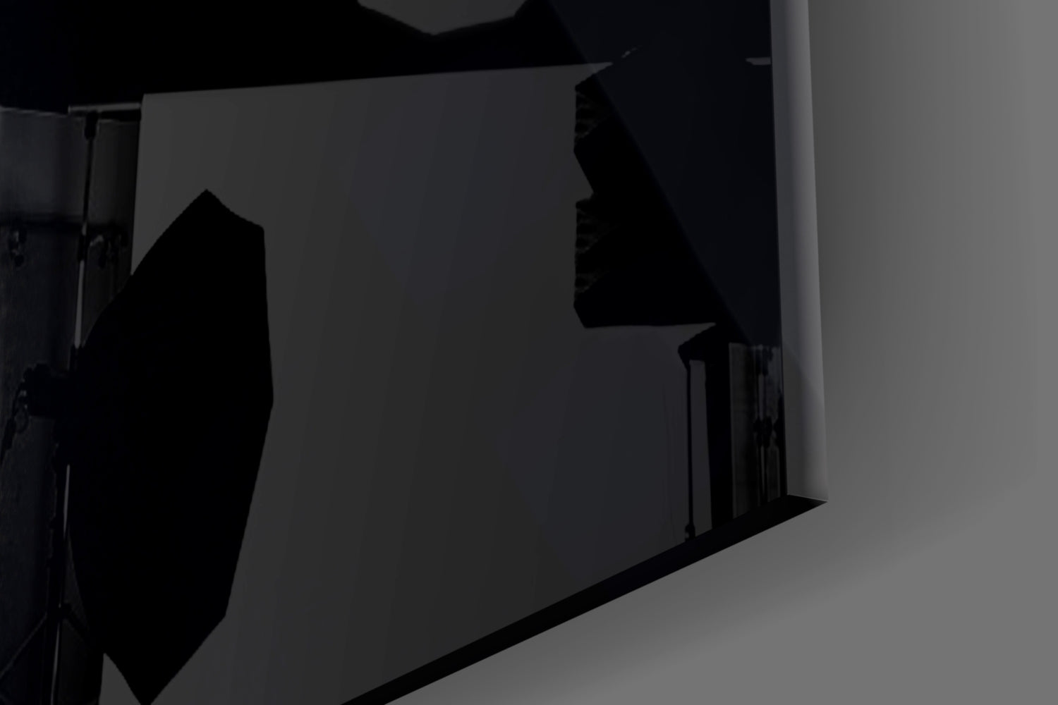 Silhouetted view of glass wall art mounted on light gray wall, showing dark profile of woman's face in side angle installation shot.