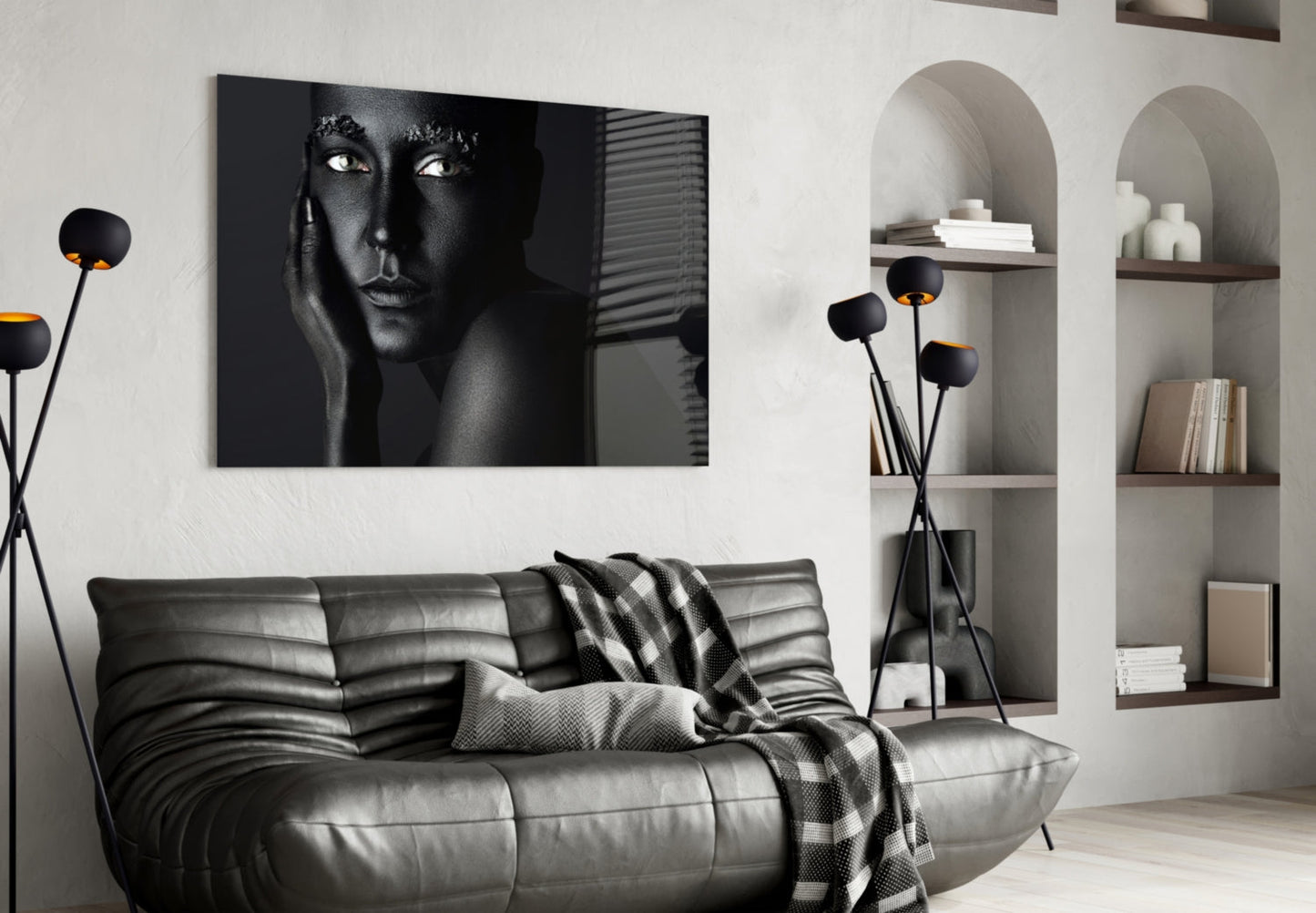 Black and white portrait of a woman's face on glass wall art displayed above a gray leather sofa in a modern living room.