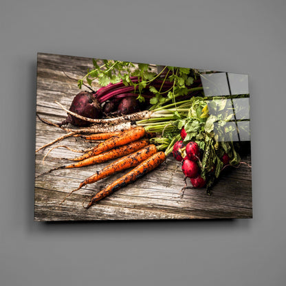 Glass wall art displaying fresh carrots, beets, and radishes with green stems on rustic wooden surface.