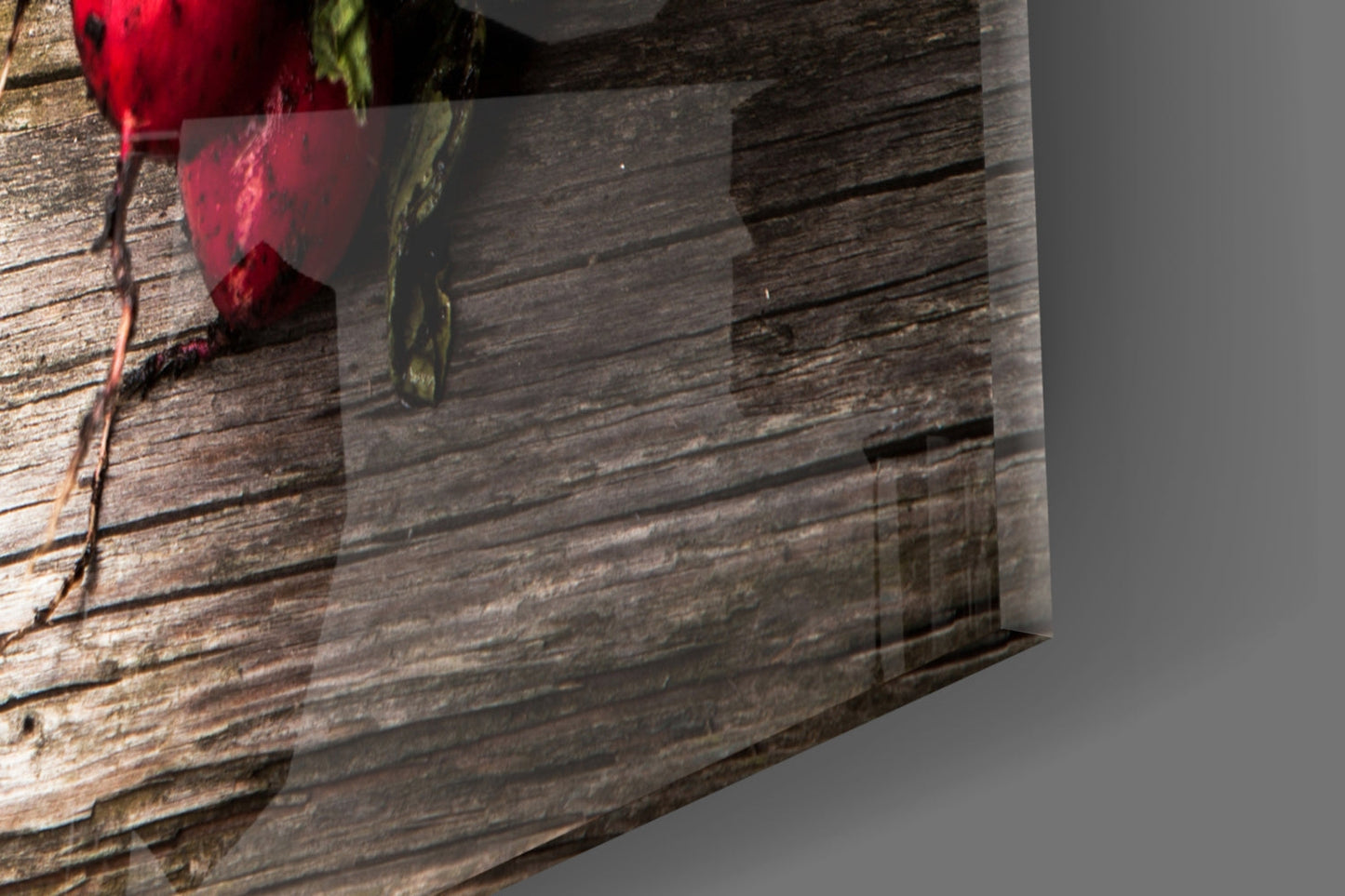 Glass wall art with red carrot and green radish designs displayed against rustic wooden plank background.