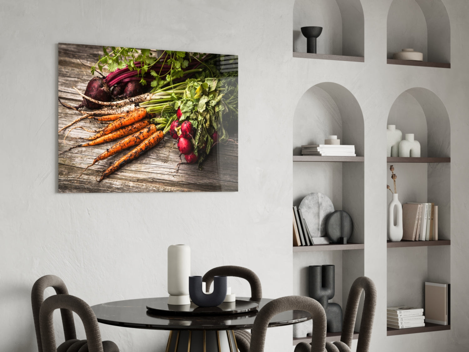 Glass wall art displaying fresh carrots and radishes with green stems on rustic wood, hung in modern dining room above round black table.