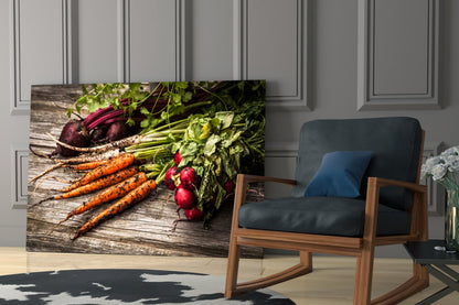 Glass wall art displaying fresh carrots, beets, and radishes with green leafy tops on rustic wood, displayed in modern living room setting.