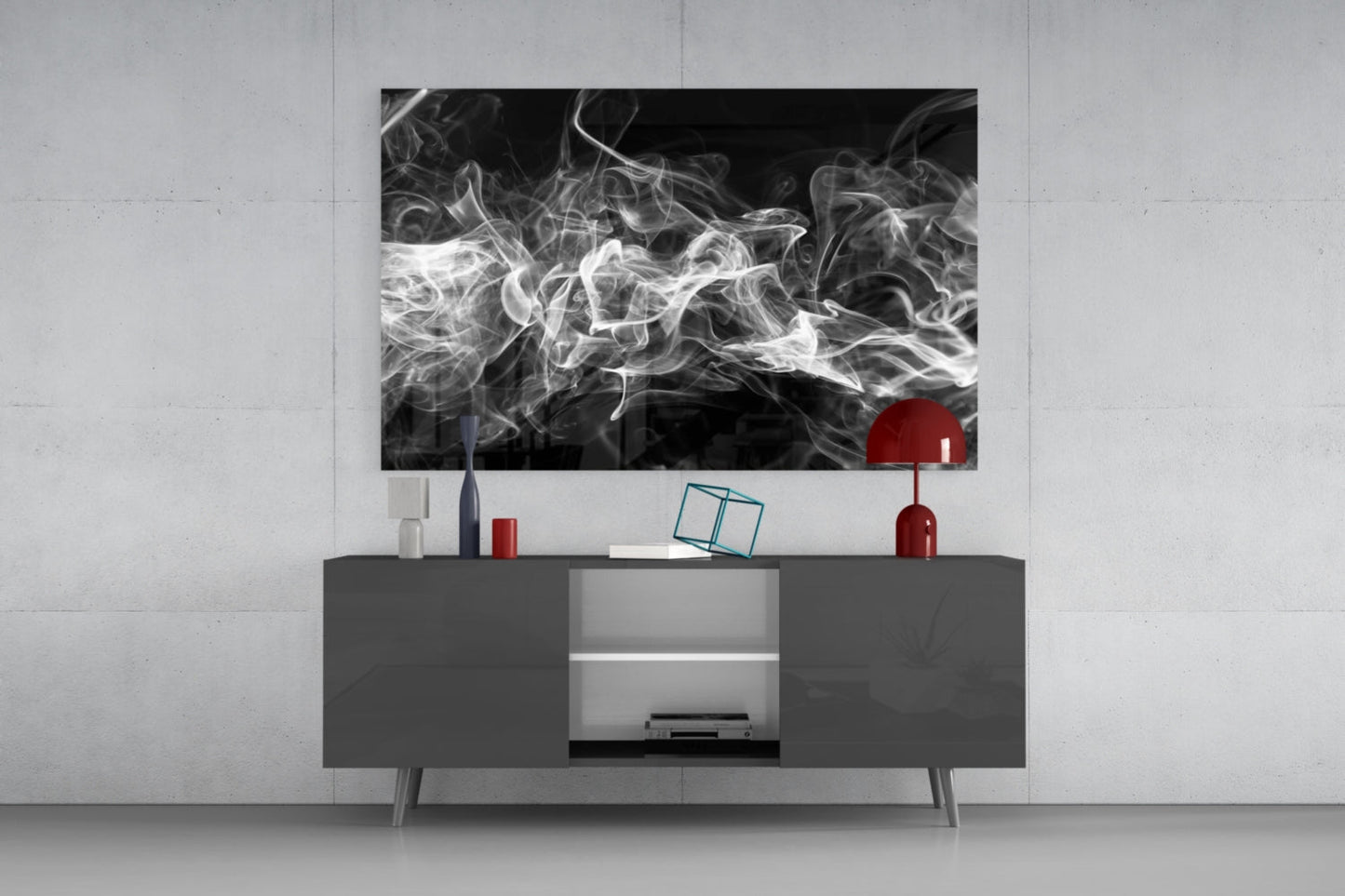 Black and white smoke glass artwork displayed above gray media console with red decorative objects and open shelving in modern living room setting.