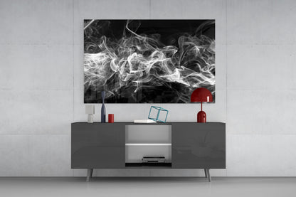 Black and white smoke glass artwork displayed above gray media console with red decorative objects and open shelving in modern living room setting.