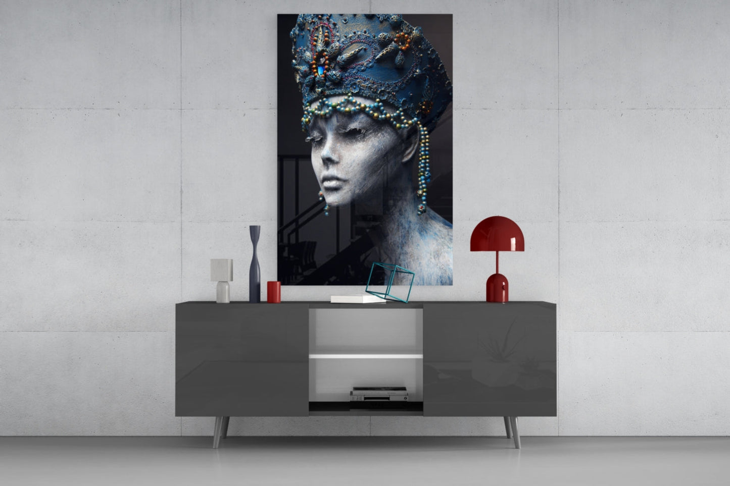 Glass wall art featuring a monochromatic female portrait with ornate blue headdress and beaded details displayed above a modern gray console table.