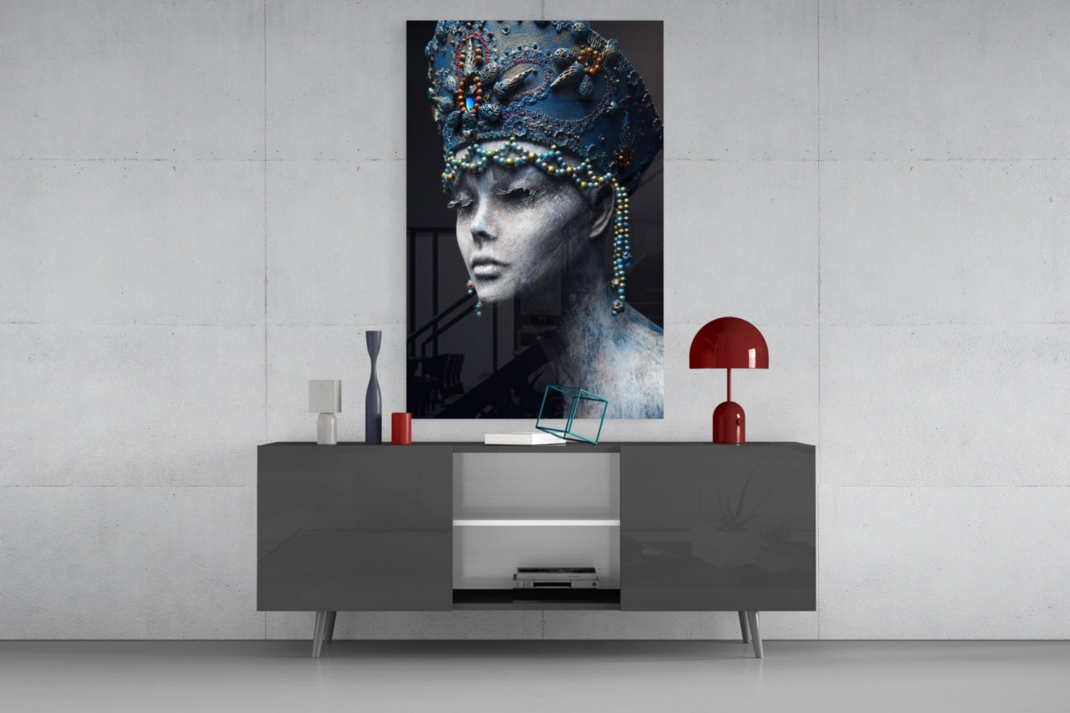 Glass wall art featuring a monochromatic female portrait with ornate blue headdress and beaded details displayed above a modern gray console table.