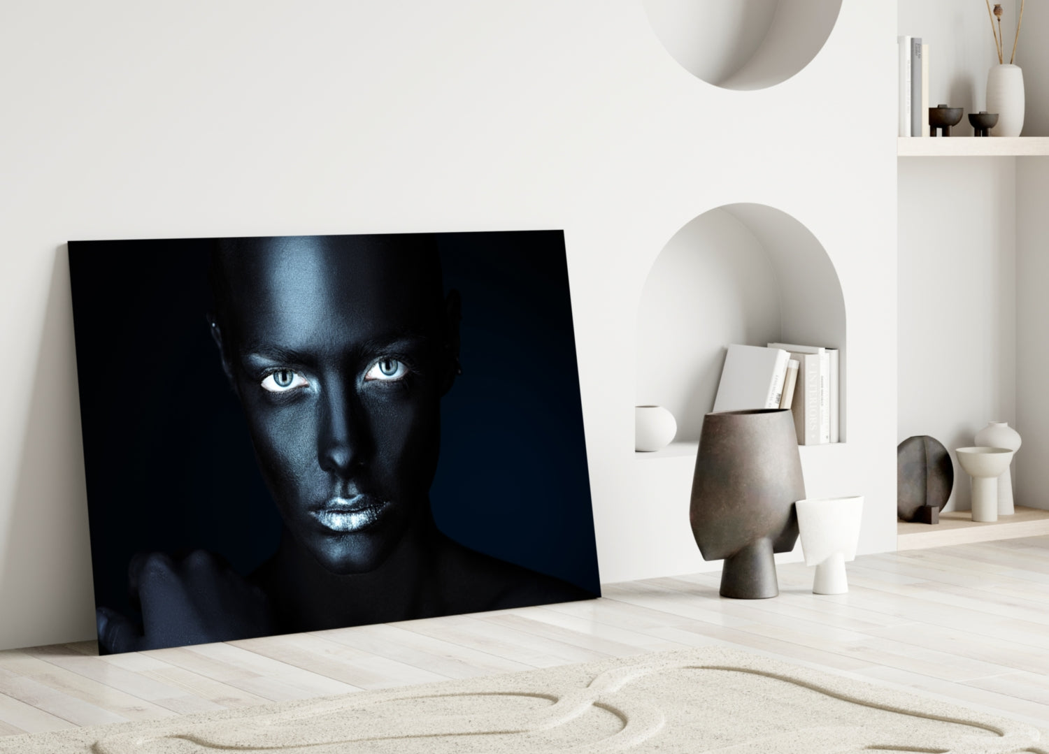 Dark portrait of woman with pale eyes leaning against white wall in minimalist room with sculptural decor.