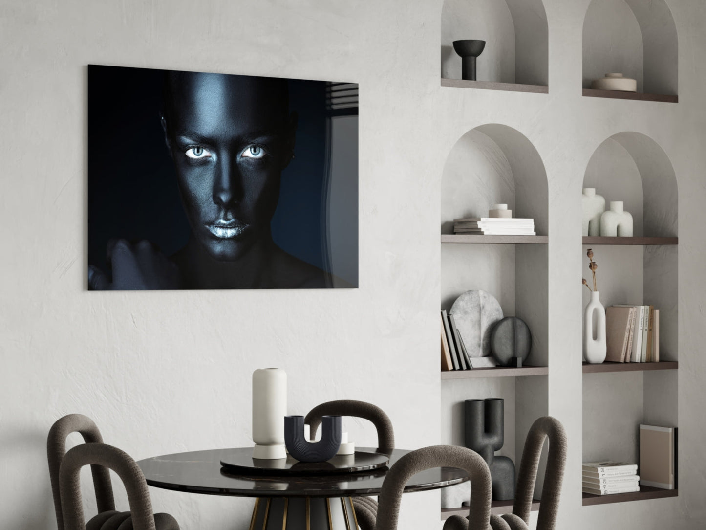 Glass wall art featuring a high-contrast portrait of a woman's face with striking white eyes against black skin tones, displayed above a round dining table.