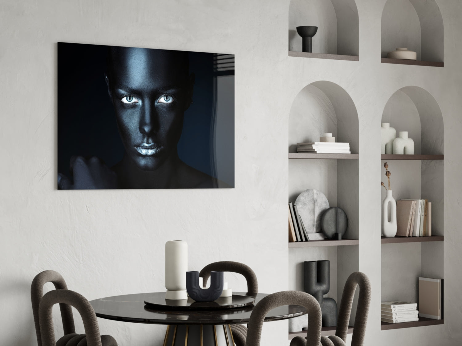 Glass wall art featuring a high-contrast portrait of a woman's face with striking white eyes against black skin tones, displayed above a round dining table.