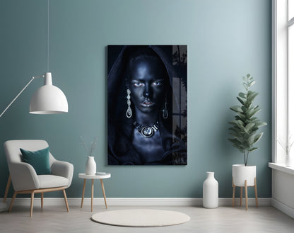 Glass wall art depicting a woman's portrait with dramatic lighting, jeweled accessories, and dark tones, displayed in a minimalist room setting.