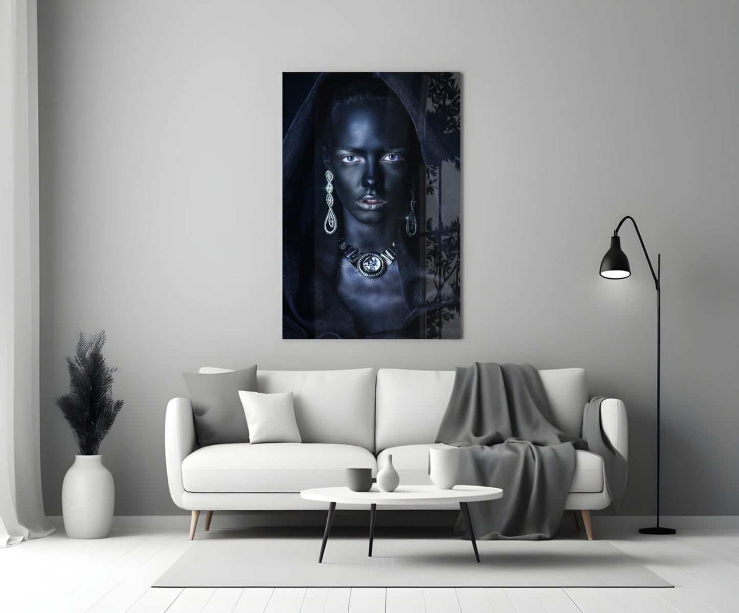 Glass wall art depicting a woman with dark skin and silver jewelry against a dark background, displayed above a white sofa in a modern living room.