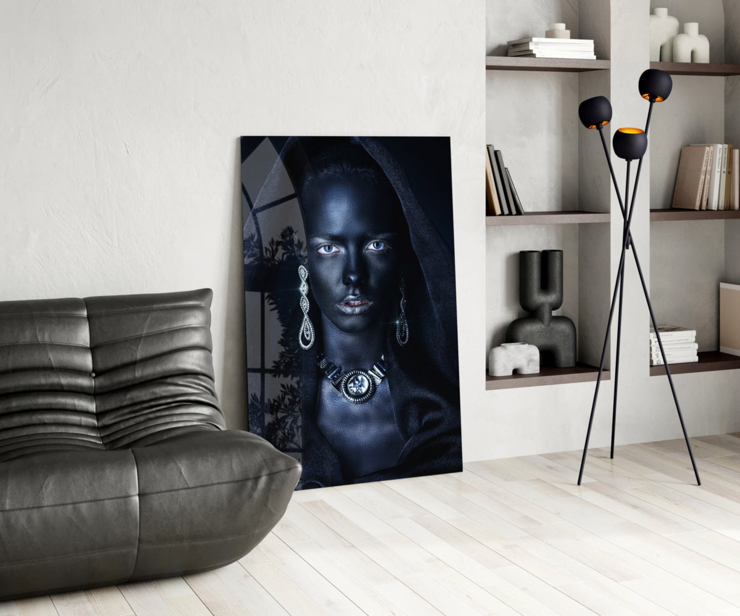 Modern living room interior featuring a glass portrait artwork of a woman with blue eyes and jewelry, displayed next to a gray leather sofa.