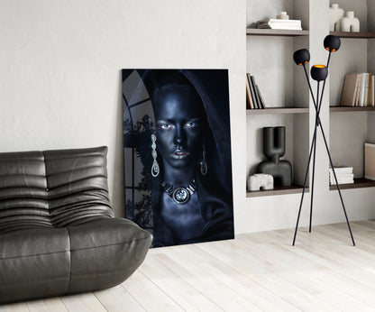 Modern living room interior featuring a glass portrait artwork of a woman with blue eyes and jewelry, displayed next to a gray leather sofa.