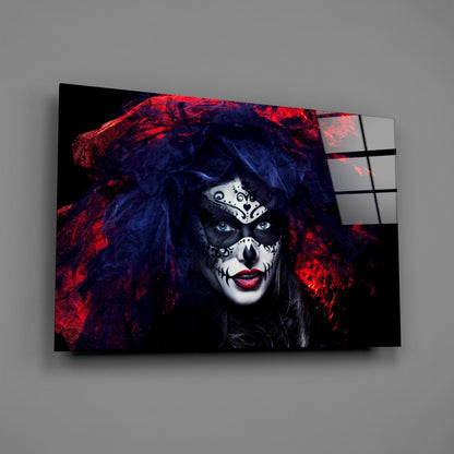 Woman with skull face makeup and blue hair wearing red and black fabric, displayed on glass wall art panel angled against gray background.