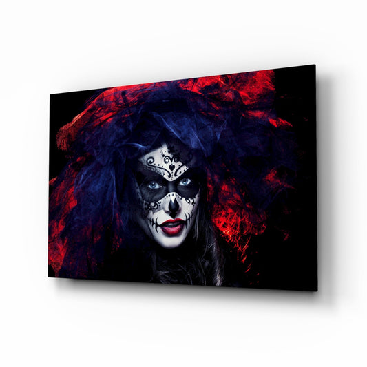 Woman with skull face paint and ornate white mask wearing dark red and blue fabric hood, displayed on glass wall art panel.
