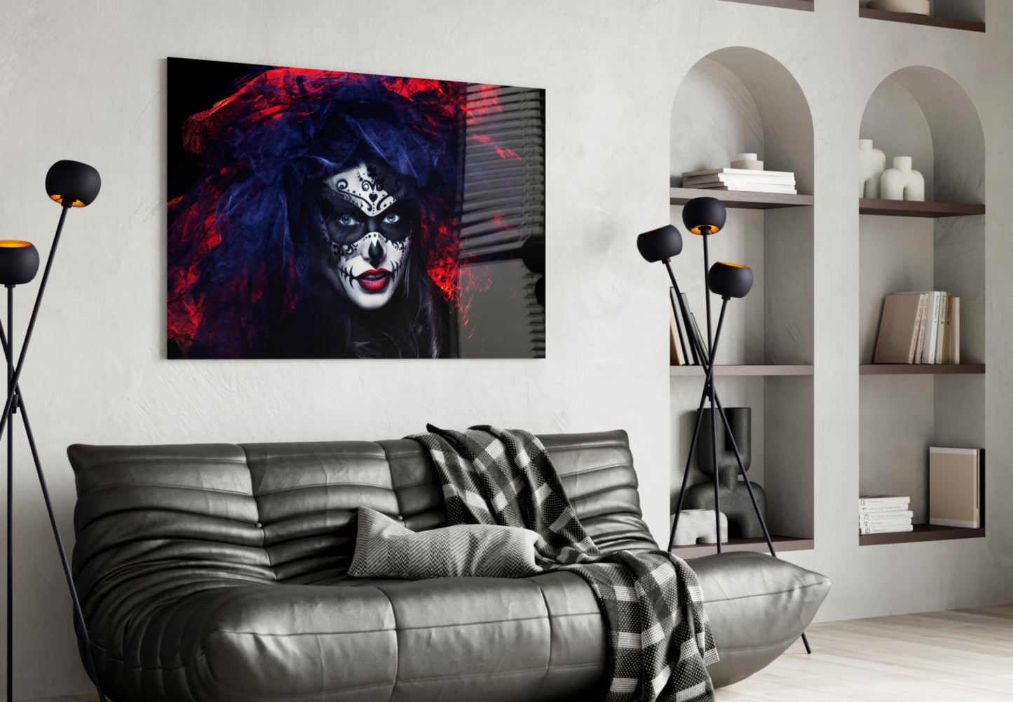 Glass wall art featuring dramatic portrait of woman with skull makeup, red and blue lighting, displayed above gray leather sofa in modern living room.