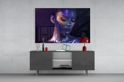 Modern living room setup displaying a glass wall art portrait of a woman's face with blue and pink sparkle effects mounted above a dark gray media console.
