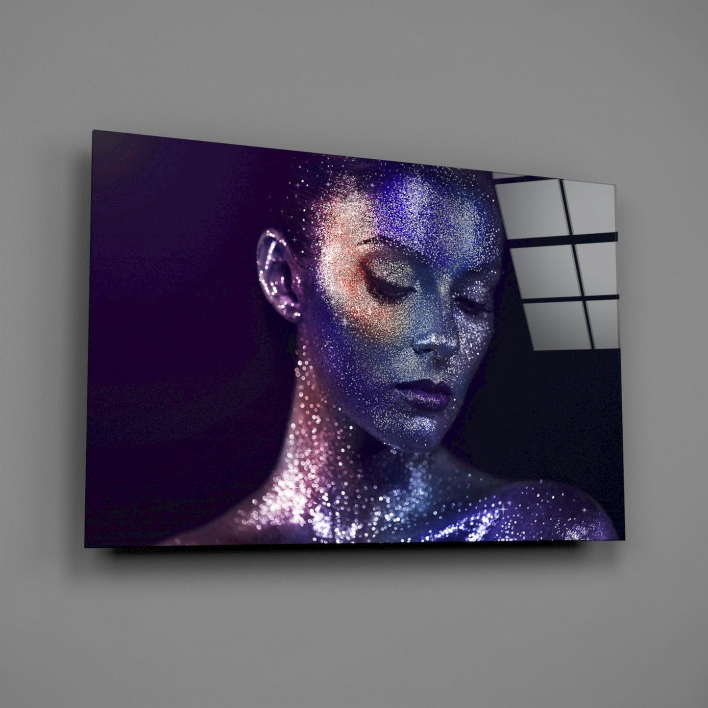 Glass wall art mounted on gray wall displaying woman's profile with purple and blue sparkle effect, right edge showing grid pattern glass panels.