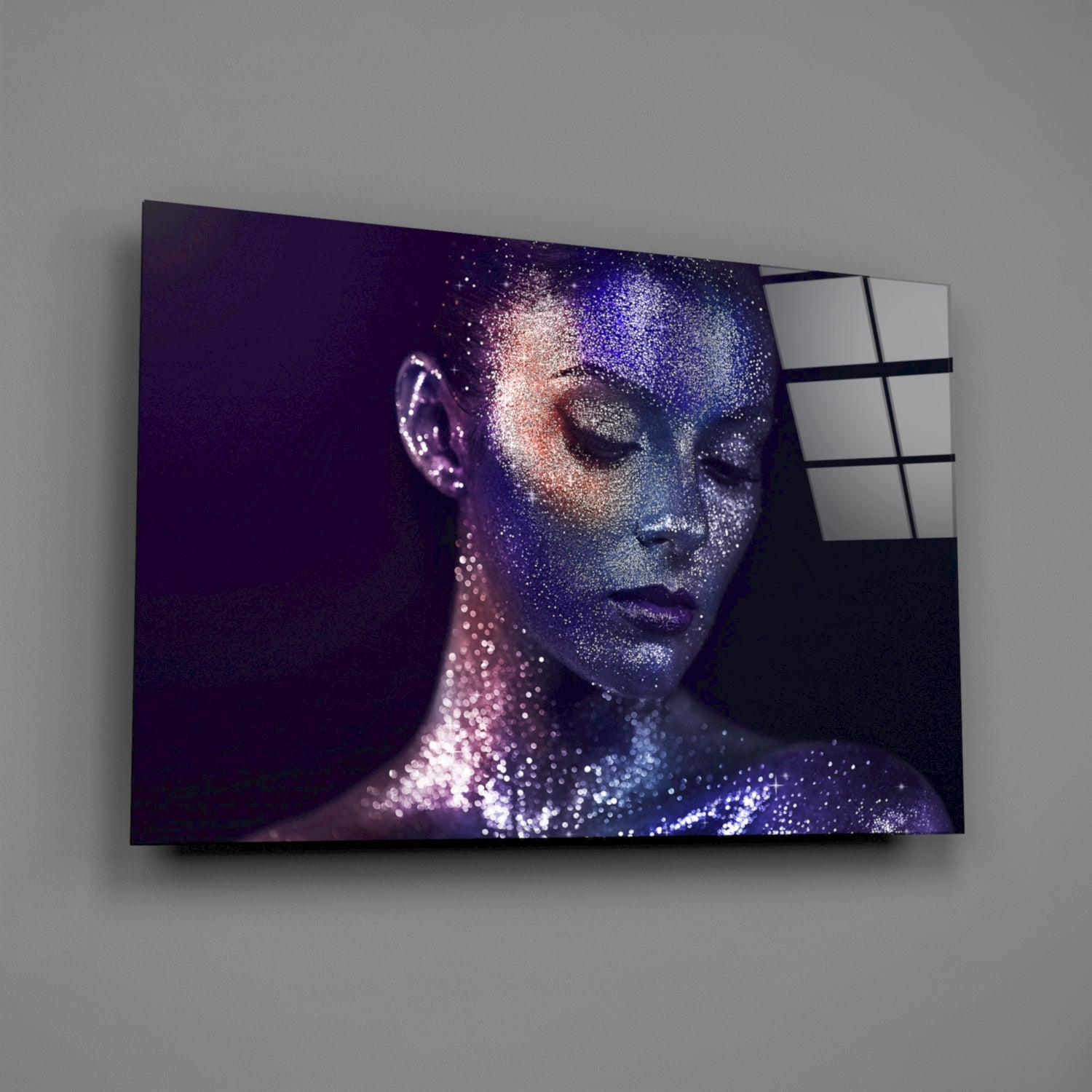 Glass wall art mounted on gray wall displaying woman's profile with purple and blue sparkle effect, right edge showing grid pattern glass panels.