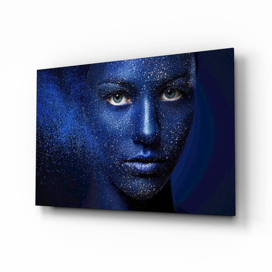 Blue and gold glittering face portrait on dark background displayed as angled glass wall art panel.