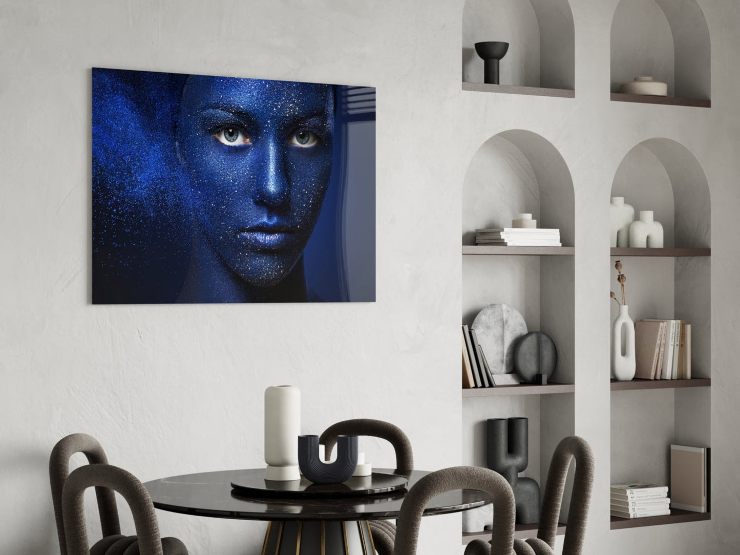 Blue-toned portrait of a woman's face with glittering texture displayed above a round black dining table with gray chairs.