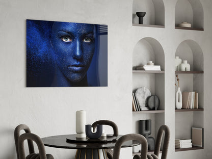 Blue-toned portrait of a woman's face with glittering texture displayed above a round black dining table with gray chairs.