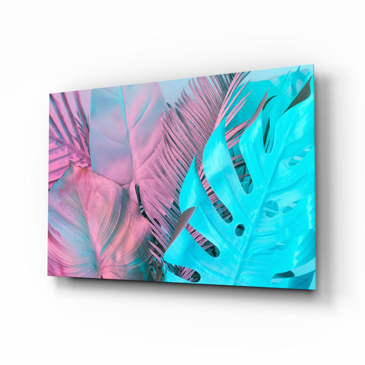 Angled perspective of glass wall art displaying pink and turquoise monstera leaves with black striped details against gradient backgrounds.