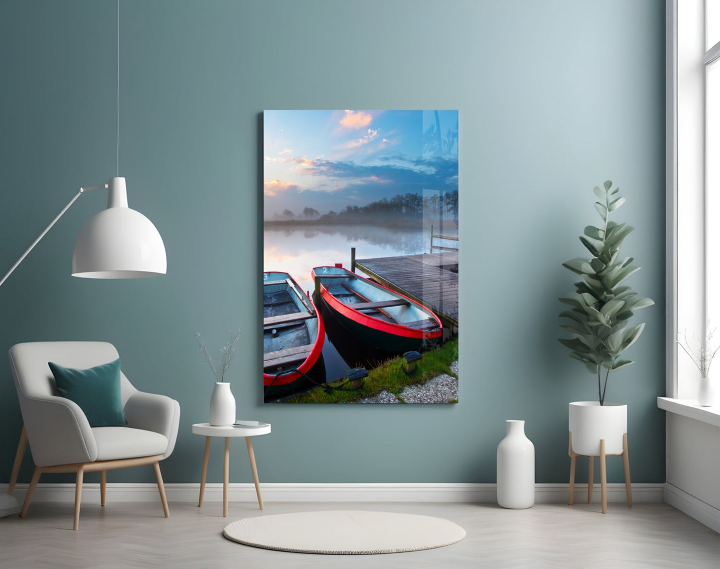 Glass wall art displaying red and blue boats on a misty lake at sunrise, hung in a contemporary room with teal walls.